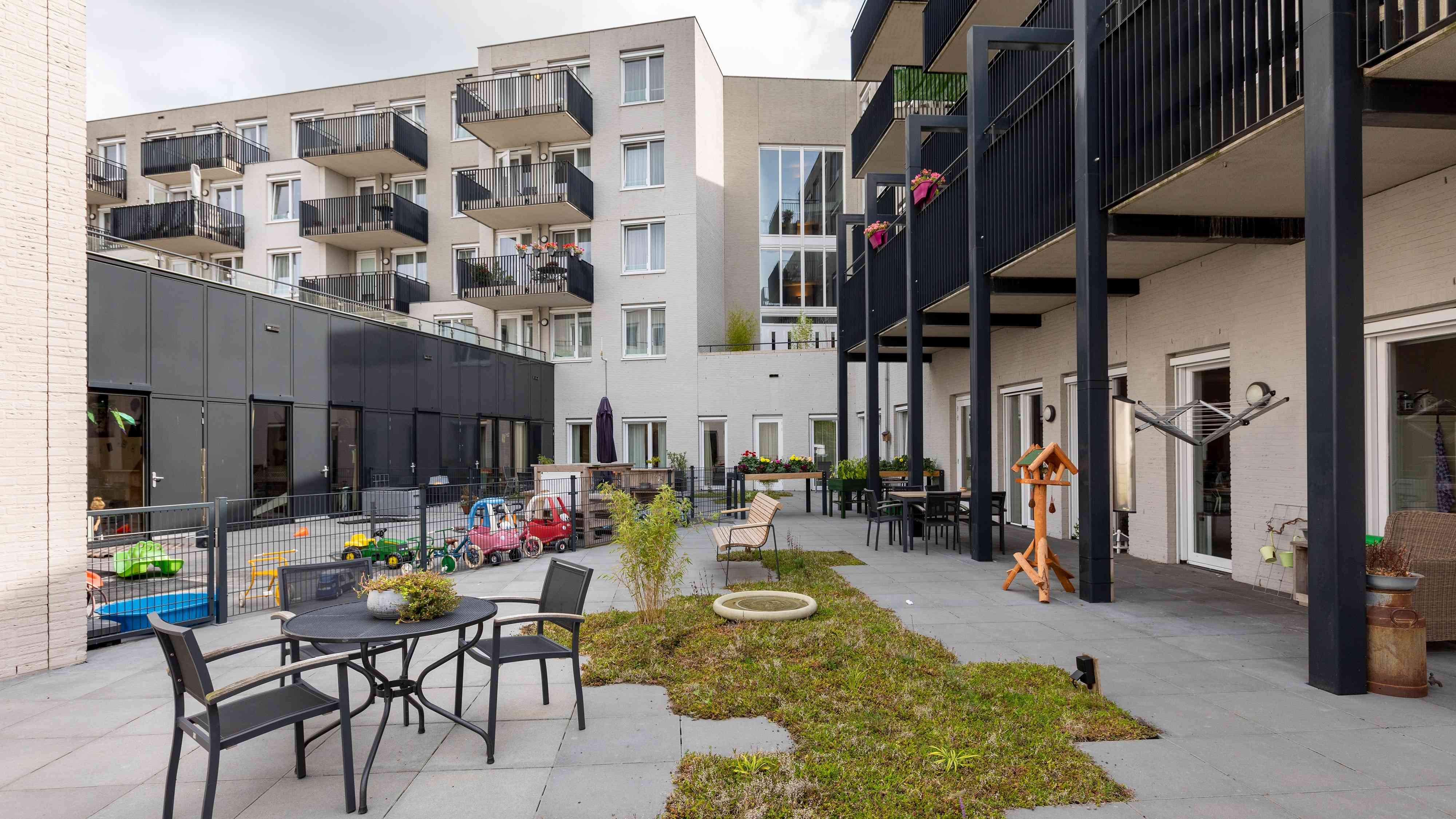 De tuin op kleinschalig wonen met uitzicht op de speelplaats van het kinderdagverblijf